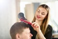 Young Girl Hairdresser Holding Dryer and Hairbrush Royalty Free Stock Photo