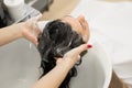 Young girl hairdresser washes her hair with shampoo and massages the head of a young woman in a modern barber salon. Royalty Free Stock Photo