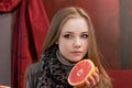 Young girl with half a grapefruit in hands on background of interior cafe Royalty Free Stock Photo