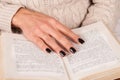 Young Girl hand with black nails holds book, woman in sweater reading book Royalty Free Stock Photo