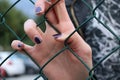 Young girl hand through green steel net close up