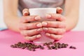 Young girl hand holding cup of coffee and coffee beans on pink desk Royalty Free Stock Photo