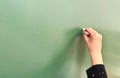 Young girl hand writing on a blank green chalkboard Royalty Free Stock Photo