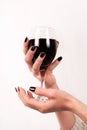 Young girl hands with black nails holding glass with red wine, close up Royalty Free Stock Photo