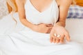 Young girl hands holding her belly, and holds pills in her hand