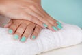 Young girl hands with a turquoise color nails polish on a white towel on desk isolated on soft blue background in studio Royalty Free Stock Photo