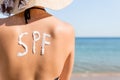 Young girl has spf word on her back made of sun cream at the beach. Sun protection factor concept