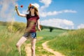 A young girl in hat is plucking a poppy flowers - by the cart road Royalty Free Stock Photo