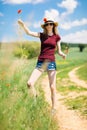 A young girl in hat rip out poppy flower with roots Royalty Free Stock Photo