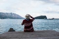 Young girl in hat sitting on wooden pier and looking the horizon Royalty Free Stock Photo