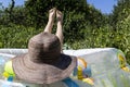 Young girl  in hat and swimsuit lying in the inflatable swimming pool. Vacation 2020 Royalty Free Stock Photo