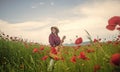 young girl in hat walk in meadow. vacation. sense of freedom. beautiful woman gather red poppy flower bouquet in field