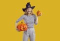 Portrait of a happy, funny woman in a witch hat holding Halloween pumpkins and laughing Royalty Free Stock Photo