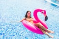 Young girl having fun and laughing on an inflatable giant pink flamingo pool float mattress in a bikini. Attractive tanned woman l Royalty Free Stock Photo