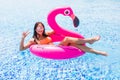 Young girl having fun and laughing on an inflatable giant pink flamingo pool float mattress in a bikini. Attractive tanned woman l Royalty Free Stock Photo