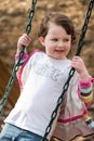 Young girl having fun outside at park on a playground swing set Royalty Free Stock Photo