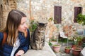 Young girl is having a nice talk with a local cat in Italy