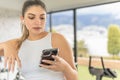 young girl with headphones looking at her cell phone during a break in the gym Royalty Free Stock Photo