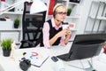 A young girl with headphones sitting at the computer table and holding a glass of coffee. Royalty Free Stock Photo