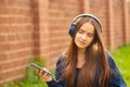 Young girl with headphones walking around the city in the summer, listening to music, enjoying, smiling Royalty Free Stock Photo