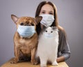 Young girl her cat and dog in medical masks during a pandemic Royalty Free Stock Photo