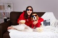 A young girl with her dog beagle is watching a movie at home.