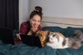 Young girl, her dog french bulldog and fluffy cat work at home in bed during quarantine Royalty Free Stock Photo