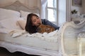 Young girl and her dog french bulldog wallow in bed Royalty Free Stock Photo
