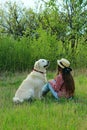 Young girl and her dog sitting on green grass. Pet and owner. People, travel, animals concept.