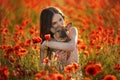 Young girl and her french bulldog puppy in a field with red poppies Royalty Free Stock Photo