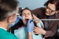 Young girl with her mother on the first dental visit. Senior pediatric dentist treating patient girl teeth