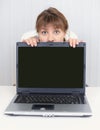 Young girl hiding behind a laptop screen Royalty Free Stock Photo