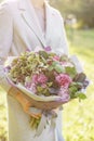 Young girl holding a beautiful spring bouquet. flower arrangement with hydrangea and garden roses. Color violet pink