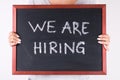 Young girl holding blackboard with chalk text We are Hiring