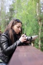 A young girl is holding a camera in her hands. Dark hair, autumn landscape. Concept woman photographer, women& x27;s art. Royalty Free Stock Photo