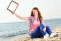 Young girl holding frame on the beach Royalty Free Stock Photo
