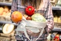 Girl holding fruits and vegetables in an eco bag on the background of the store Royalty Free Stock Photo