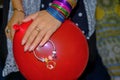 young girl holding her bracelet and red ballon