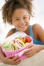 Young girl holding packed lunch in living room Royalty Free Stock Photo