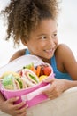 Young girl holding packed lunch in living room Royalty Free Stock Photo