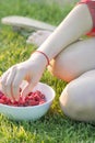 Young girl holding a plate of raspberries, sitting on green grass, summer, dessert