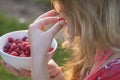 Young girl holding a plate of raspberries, sitting on green grass, summer, dessert