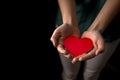 Young girl holding red heart on black background. Health insurance, organ donor day, charity concept. World health Royalty Free Stock Photo