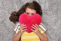 Young girl holding red plush heart lying on the carpet Royalty Free Stock Photo