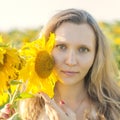 Young girl holding sunflowers outdoor shot. Portrait of beautiful blonde girl with bright yellow sunflower in hands on sunflowers Royalty Free Stock Photo