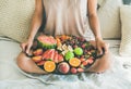 Young girl holding tray full of fresh seasonal fruits