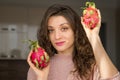 Young girl is holding two fresh ripe organic dragon fruits or pitaya, pitahaya. Exotic fruits, healthy eating concept Royalty Free Stock Photo