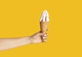 Young girl holding yummy ice cream with berry topping in waffle cone on orange background, close up of hand Royalty Free Stock Photo