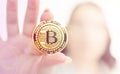 Young girl holds bitcoin in her fingers on background flares