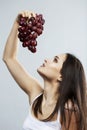 A young girl holds a bunch of purple grapes in her hand. Vitamins and health. Gray background. Space for text. Vertical Royalty Free Stock Photo